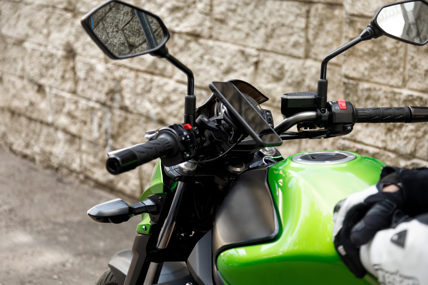 Una moto de color verde con un soporte en el que hay un smartphone